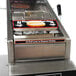 A Benchmark USA hot dog steamer machine on a counter with a hot dog label.