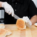 A person cutting a sandwich with a Mercer Culinary Renaissance bread knife.