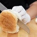 A person using a Mercer Culinary Renaissance bread knife to cut a sandwich.