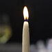 A close up of a lit ivory Sterno taper candle.