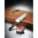 A Victorinox Santoku knife with a rosewood handle on a cutting board.