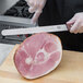 A person using a Victorinox serrated roast beef carving knife to slice meat on a cutting board.