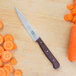 A Victorinox utility knife with a rosewood handle next to sliced carrots.