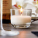 A Sterno PetiteLites clear wax candle in a glass on a table.