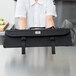 A woman holding a black Mercer Culinary knife case on a counter.