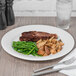 A Reserve by Libbey bone china round plate with meat, green beans, and potatoes on a table.