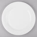 A white plate with a white rim on a gray surface.