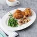 A plate of fried chicken and green beans on a Libbey bone china oval platter on a table.