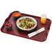 A black Cambro Camchiller tray with food including salad and fruit on it.
