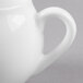 A close-up of a white Reserve by Libbey bone china creamer with a handle.