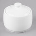A white bone china sugar pot with a lid on a gray surface.