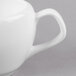 A close-up of a white bone china sauce boat with a handle.