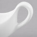 A white bone china sauce boat with a curved handle.