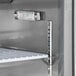 An Avantco stainless steel refrigerator with a thermometer on a shelf.