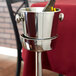 A silver Vollrath wine bucket stand holding a wine bottle.