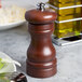 A Fletchers' Mill walnut stain wooden pepper mill on a table.