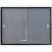 A grey fabric Quartet bulletin board with a graphite aluminum frame and enclosed glass doors.