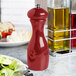 A Fletchers' Mill Marsala cinnabar pepper mill on a table next to a plate of salad.