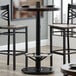 A black metal bar table with a Lancaster Table & Seating Chrome Foot Ring on the base.