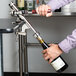 A person using a Franmara Cedon nickel-plated counter mount wine bottle opener to open a bottle of wine on a counter in a bar.