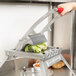 A hand using a Vollrath Redco Lettuce King vegetable cutter to slice lettuce.