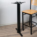 A black metal bar table with a Lancaster Table & Seating black metal bar height pole.