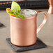 An Acopa copper Moscow Mule mug with ice and fruit garnish.