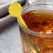A glass of iced tea with a yellow WNA Comet disc stirrer.