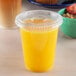 A clear plastic lid with a straw slot on a plastic cup of yellow liquid.