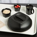 A black tray with a black Cambro bowl and mug on it filled with oatmeal and strawberries.