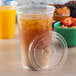 A plastic cup with a Fabri-Kal clear plastic lid and a brown drink inside it.