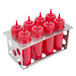 A stainless steel Eagle Group bottle holder filled with eight red bottles with red and white tops.