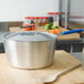 A Vollrath Wear-Ever sauce pan with a spoon on a cutting board.