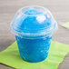 A clear plastic squat dome lid with a blue slushy and a straw.