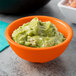 A white Tablecraft ramekin filled with guacamole on a table.
