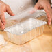 A person holding a clear plastic dome lid over a clear plastic container filled with dough.