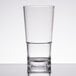A close-up of a stackable clear plastic tasting glass filled with water.