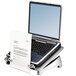 A Fellowes black and silver laptop riser with a laptop and paper on it.