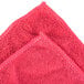 A close up of a red Unger SmartColor Microfiber cleaning cloth with white stitching.