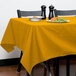 A table with a gold Intedge tablecloth and a plate of food.