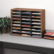 A Fellowes medium oak literature organizer on a desk with many different types of papers.