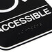A black and white Vollrath Traex Handicap Accessible sign with the word "accessible" in white and braille.