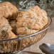 A Clipper Mill chrome plated iron oval wire basket filled with croissants.