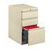 A white HON mobile pedestal filing cabinet with a red file drawer.