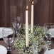 A table set with ivory Hyoola taper candles in a wreath of white flowers.