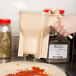 A hand using a Vollrath Batter Boss diffuser to pour batter over a pizza.