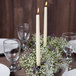 A table set with Hyoola ivory taper candles in a wreath of white flowers.