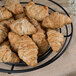 A black Clipper Mill round wire basket filled with croissants.