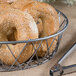 A sesame seed bagel in a Clipper Mill iron wire basket.
