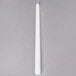 A 12" white Hyoola taper candle on a gray surface.